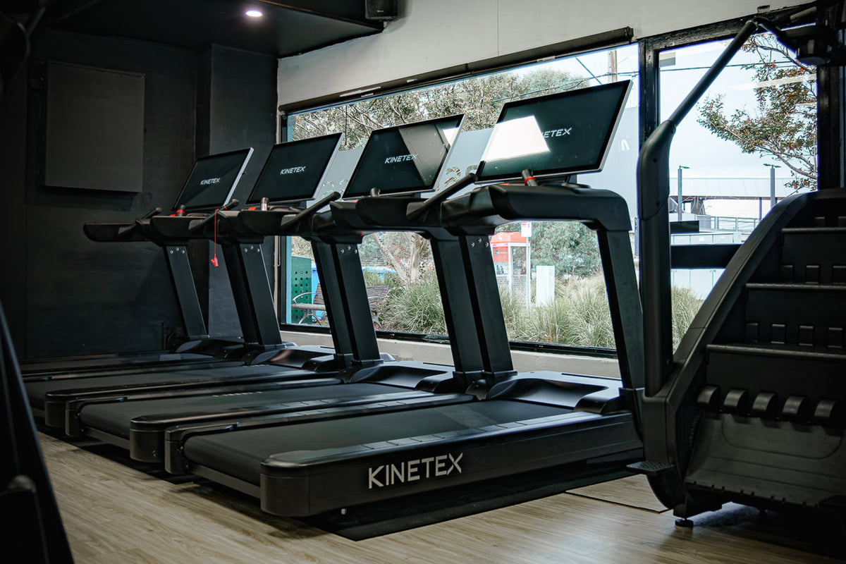 Row of commercial treadmills in a bright gym